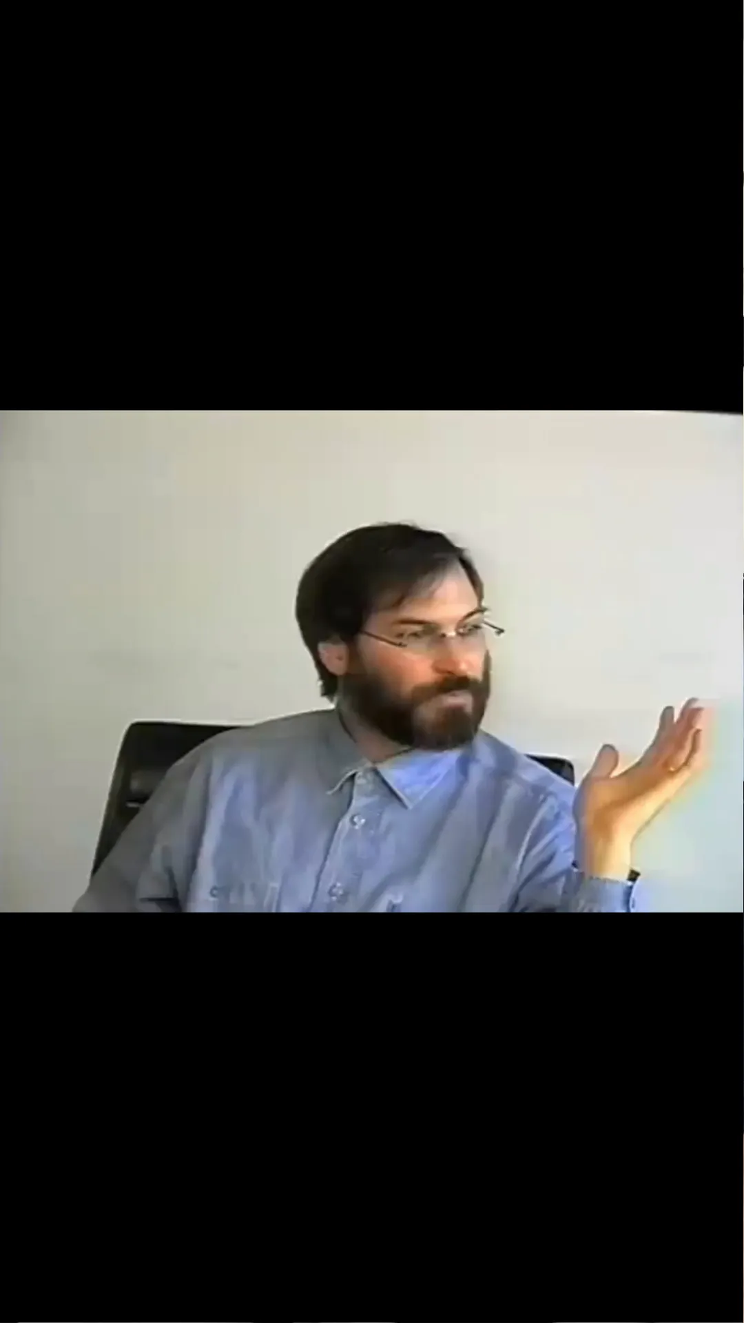 Steve Jobs wearing a blue button-down shirt speaking during an interview