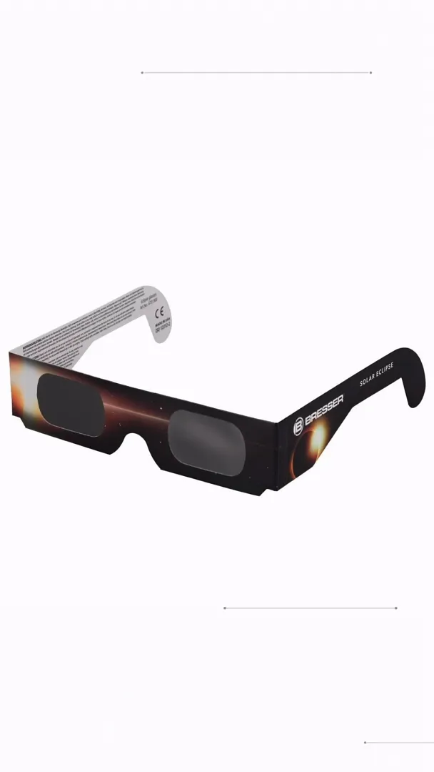 Cardboard solar eclipse glasses with dark rectangular viewing panes resting on a plain white surface