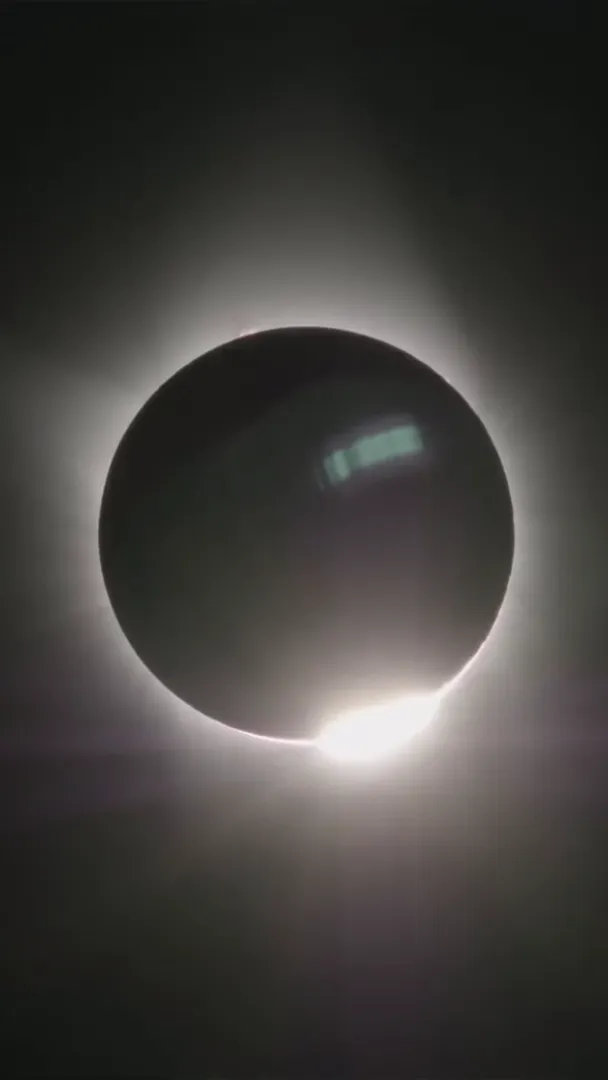 Dark silhouette of the moon completely covering the sun with a glowing bright ring around the edge