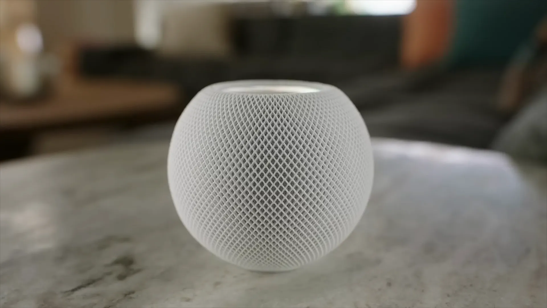 White HomePod mini sitting on a marble table in a modern living room